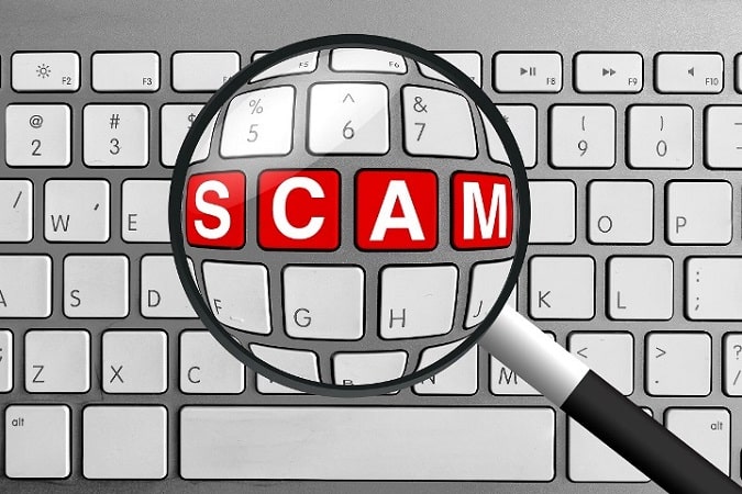 How to Avoid Affiliate Marketing Scams — Computer Keyboard with Red Scam Buttons and Magnifying Glass.